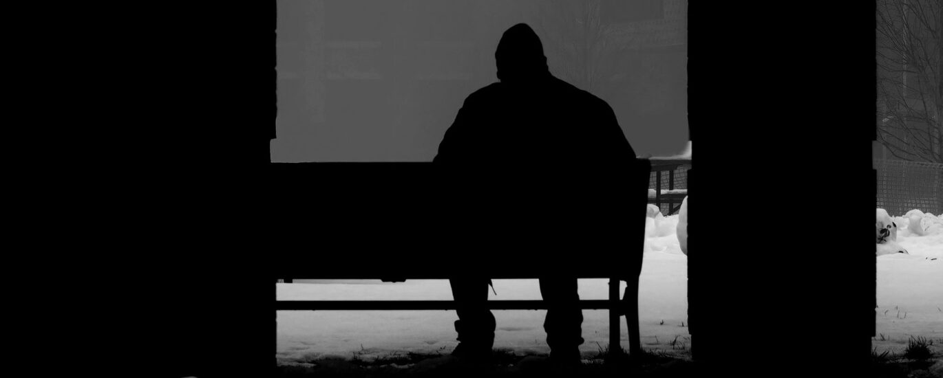 Silhouette of a person sat on a bench in the snow